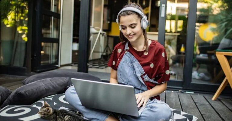 A young woman working on a laptop, creating digital products for her side hustle and passive income