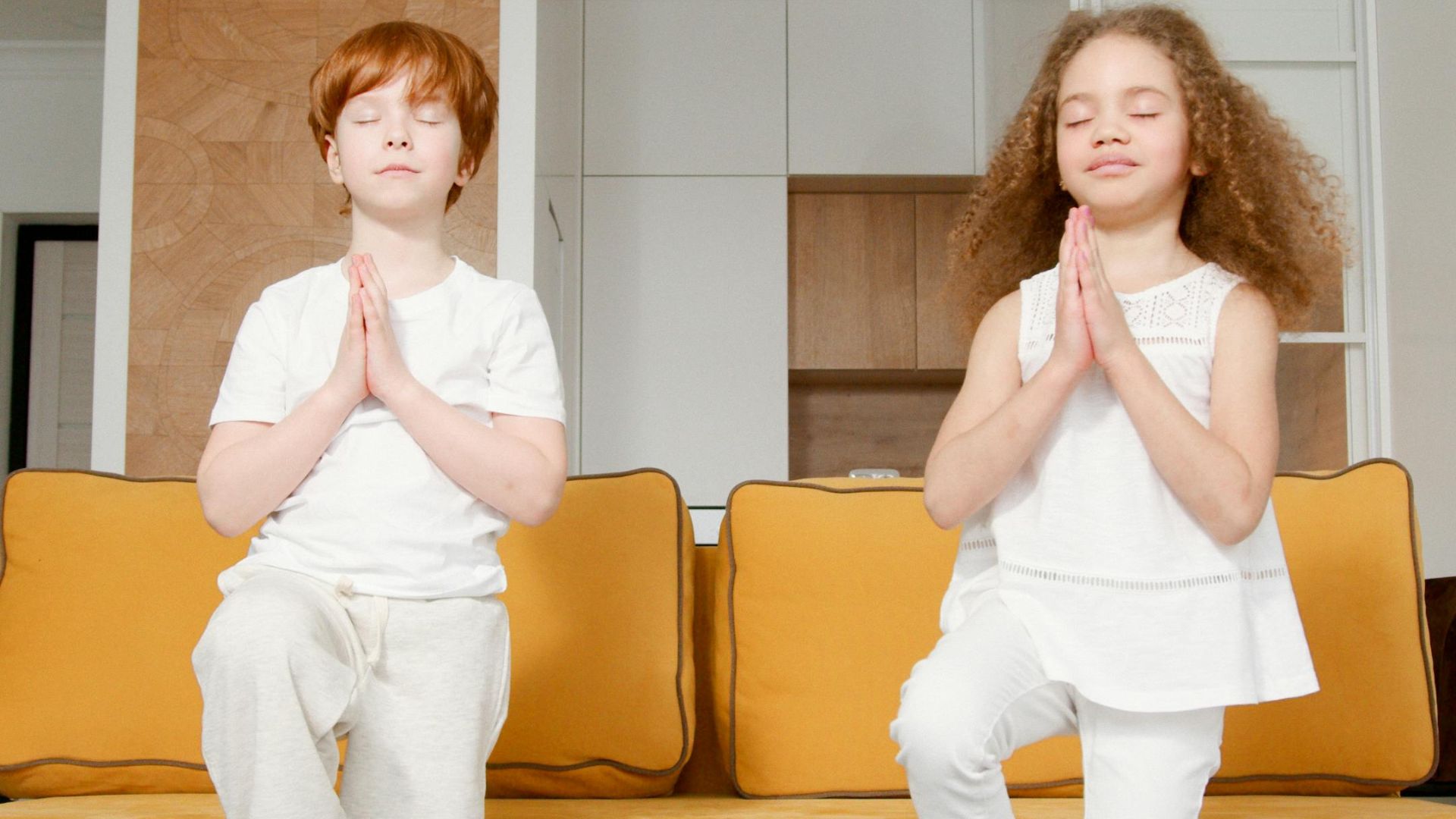 Two young children doing yoga exercises together, promoting a healthy and active lifestyle.