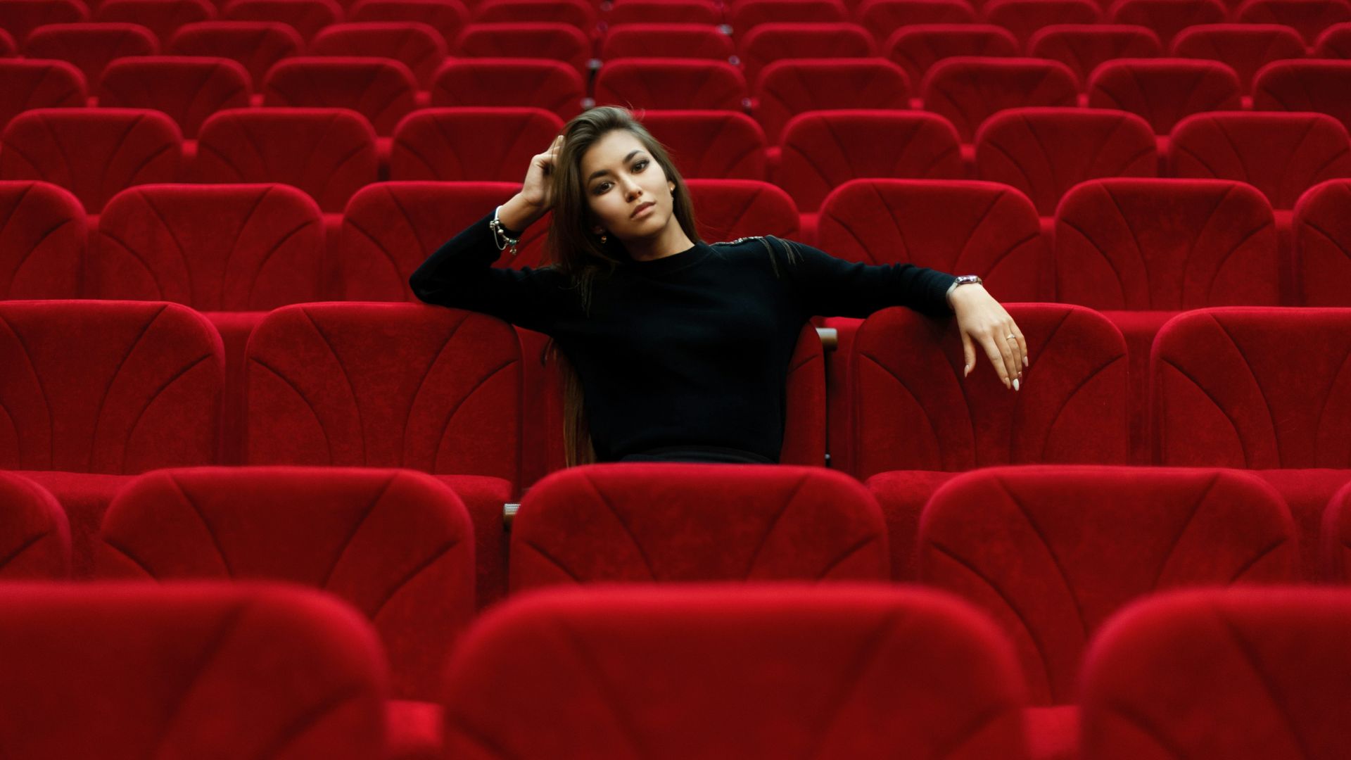 An exhausted woman sitting alone in a movie theater, reflecting emotional fatigue caused by modern movies